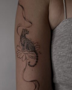 Mikrorealistyczny tatuaż pantery z motywami florystycznymi, wykonany na kobiecym bicepsie. Styl inspirowany naturą i fantastyką.